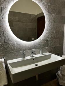 ein Badezimmer mit einem weißen Waschbecken und einem Spiegel in der Unterkunft Sartinicco Apartment in Montepulciano