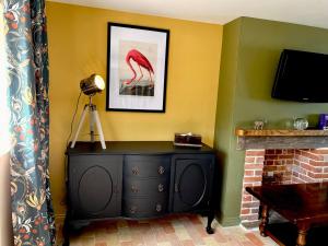 a room with a black dresser next to a fireplace at The Hayloft in Gestingthorpe