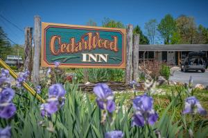 a sign for a credentialed inn with purple flowers at CedarWood Inn in Hendersonville