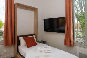Schlafzimmer mit einem Bett, einem TV und einem Fenster in der Unterkunft Villa Forestière Studio L'Acacia in Quincy-Voisins