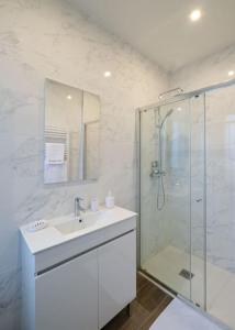 ein weißes Bad mit einem Waschbecken und einer Dusche in der Unterkunft Villa Forestière Studio L'Acacia in Quincy-Voisins
