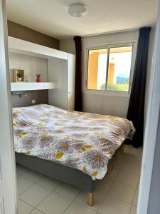 a bedroom with a bed with a floral comforter and a window at Vue mer et sur la baie de Cannes piscine 450m2 randonnée VTT au pied de l Esterel in Théoule-sur-Mer
