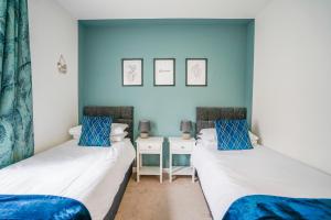 two beds in a room with blue walls at The Augustine - Modern two Bed Ground floor apartment with parking in Canterbury