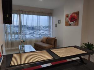 een woonkamer met een tafel, een stoel en een raam bij Suite Ejecutiva en excelente ubicación con Piscina-Parqueo-Gym-Seguridad 24/7 in Guayaquil