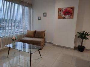 een woonkamer met een stoel en een glazen tafel bij Suite Ejecutiva en excelente ubicación con Piscina-Parqueo-Gym-Seguridad 24/7 in Guayaquil