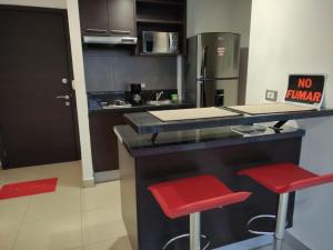 a kitchen with a counter and two red stools at Suite Ejecutiva en excelente ubicación con Piscina-Parqueo-Gym-Seguridad 24/7 in Guayaquil