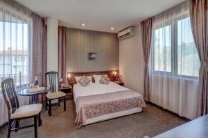 a hotel room with a bed and a table and chairs at Ellinis Hotel in Varna City