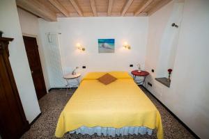 a bedroom with a yellow bed with two tables at CodeminCampiglia Casa Vista Mare con Giardino in Campiglia