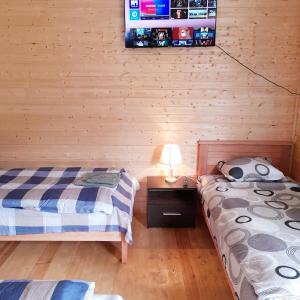 a bedroom with two beds and a tv on the wall at Wooden house ,,Tsunda" in Vardzia
