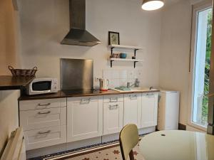 cocina con armarios blancos, mesa y microondas en L'Annexe de la corniche, en Chaumont
