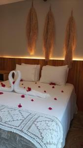 een slaapkamer met een wit bed met rozen erop bij NORI POUSADA in São Miguel dos Milagres