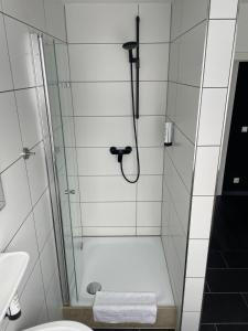 een badkamer met een douche en een glazen deur bij MOTELO Bielefeld - Smart HOTEL in Bielefeld