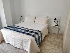 uma cama branca com lençóis azuis e brancos e duas lâmpadas em Matera Like Home - rooms - Via del Corso em Matera