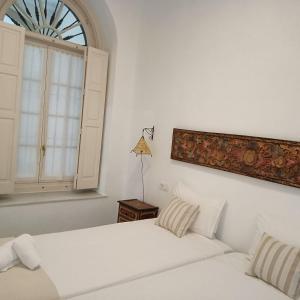 une chambre blanche avec deux lits et une fenêtre dans l'établissement Jerez Palace House, à Jerez de la Frontera