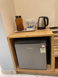 a small refrigerator under a wooden stand with a table at The Cocoon in Dehradun