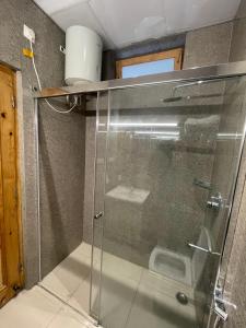 una doccia con porta in vetro in bagno di The Cocoon a Dehradun