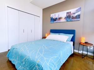 a bedroom with a bed with a blue comforter at 2BR condo in downtown, w/ view+parking in Calgary
