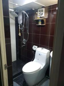 a bathroom with a toilet and a phone on the wall at The Tranquil Haven in Manila