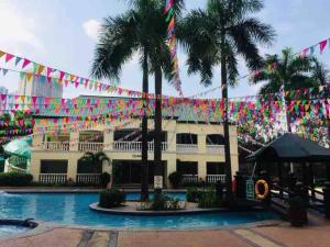 a pool with flags and palm trees in front of a hotel at The Tranquil Haven in Manila