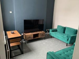 a living room with two green couches and a tv at Ayresome House in Middlesbrough