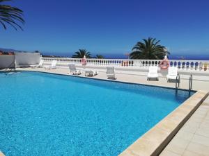ein Swimmingpool mit Stühlen und das Meer im Hintergrund in der Unterkunft Sunset La Palmita in La Victoria de Acentejo