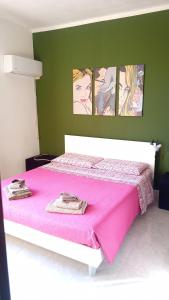 a bedroom with a pink bed with four pictures on the wall at Fior di sole in Maracalagonis