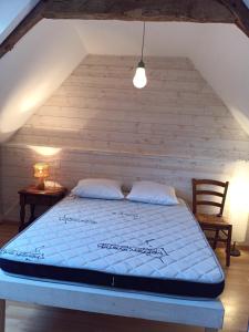 Bett in einem Zimmer mit einer Holzwand in der Unterkunft Les Berthaumes in Clécy