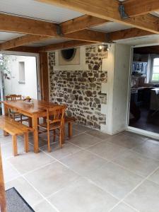 une salle à manger avec une table en bois et un mur en pierre dans l'établissement Les Berthaumes, à Clécy