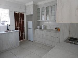 a white kitchen with a sink and a refrigerator at Grassland 4 (Townhouse) in Bloemfontein