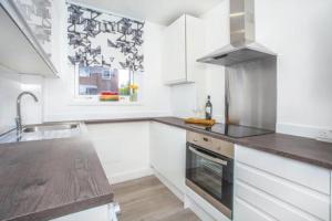 a white kitchen with a sink and a stove at 2 minutes from Hyde Park, Private Room F in London