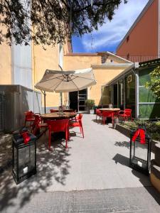 un patio con mesas, sillas y una sombrilla en Fabric Hostel, en Portici