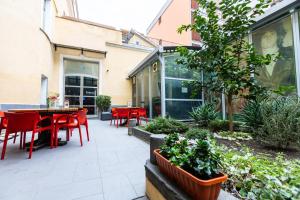 un patio con sillas rojas, mesas y plantas en Fabric Hostel, en Portici