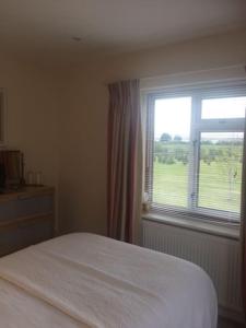 a bedroom with a white bed and a window at Cotswold edge guest suite with Broadway Hill view in Badsey