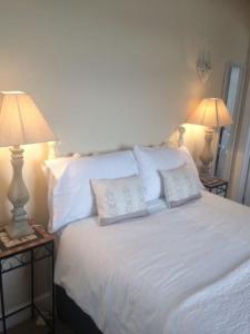 una camera con un letto bianco e 2 lampade di Cotswold edge guest suite with Broadway Hill view a Badsey