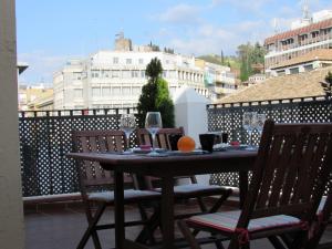 una mesa con 2 sillas y una naranja en el balcón en Apartamentos Ilíberis, en Granada