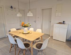 a dining room table with white chairs and a vase of flowers at Apartments Nina in Rab