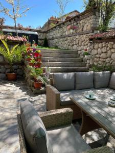 a patio with a table and chairs and a stone wall at Къща за гости Александра in Dobrinishte