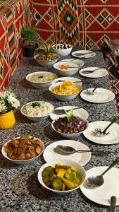una mesa con muchos platos de comida. en Wadi Rum Sunset Camp en Wadi Rum