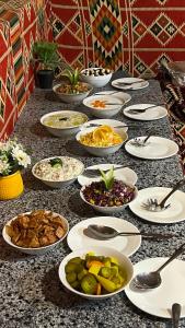 a table with many plates of food on it at Wadi Rum Sunset Camp in Wadi Rum