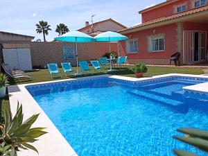 einen Pool mit Stühlen und Sonnenschirmen neben einem Haus in der Unterkunft El Capricho de Espartinas in Espartinas