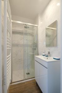 a white bathroom with a shower and a sink at Villa Forestière Appart Le Cèdre in Quincy-Voisins