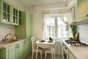 uma cozinha com armários verdes e um lavatório em METROPOLE APARTMENTS ATENEUM RESIDENCE em Bucareste