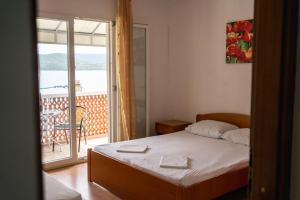 1 dormitorio con cama y vistas a un balcón en Matijaš Rooms - 20m from the beach, en Klek
