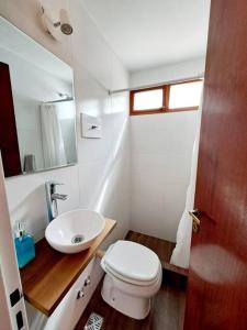 uma casa de banho com um WC branco e um lavatório. em Duplex Besugo em Pinamar