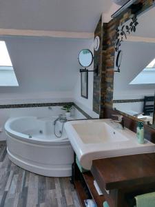 ein Badezimmer mit einer großen Badewanne und einem Waschbecken in der Unterkunft Gite & Spa Au pommier fleuri et son "Appart" indépendant in Drusenheim