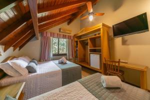 a bedroom with two beds and a desk and a television at Pousada Monte Felice Recanto da Lua in Gramado
