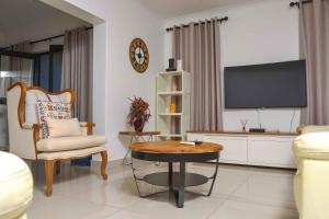 a living room with a tv and a table and a chair at acaciaoptimumstay in Gaborone