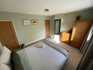 a bedroom with a white bed and a wooden dresser at Rasen Cottage in Lincolnshire
