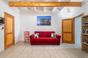 a living room with a red couch and a chair at Dery Alghero Holiday La Torre in Alghero