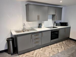 a kitchen with gray cabinets and a sink at Maxwell's Corner, Modern Coastal Apartment in North Shields